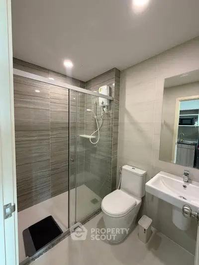 Modern bathroom with glass shower enclosure and sleek fixtures in a contemporary apartment.