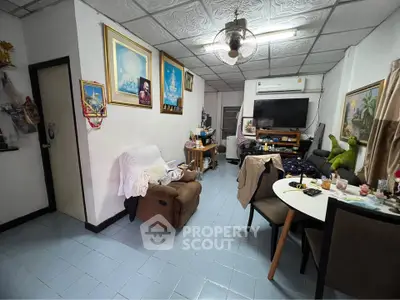 Cozy living room with eclectic decor and dining area, featuring comfortable seating and wall art.