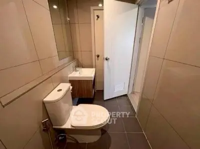 Modern bathroom with sleek design and neutral tiles, featuring a compact layout.