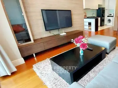 Modern living room with sleek furniture and open kitchen layout, featuring a wall-mounted TV and stylish decor.