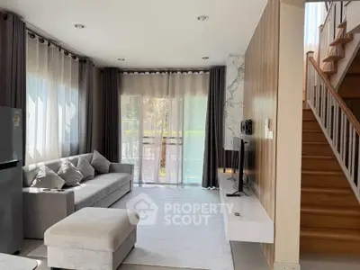 Modern living room with elegant decor and natural light, featuring a cozy sofa and stylish staircase.