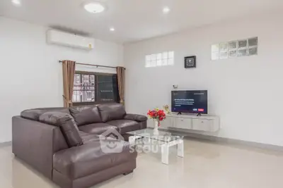 Spacious modern living room with leather sofa and wall-mounted TV, perfect for relaxation.