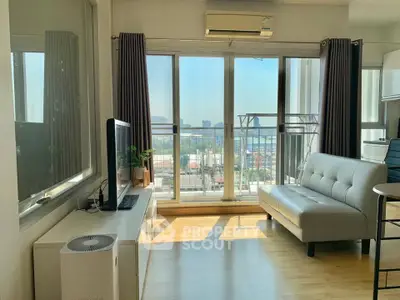 Bright living room with balcony and city view, featuring modern furniture and large windows.