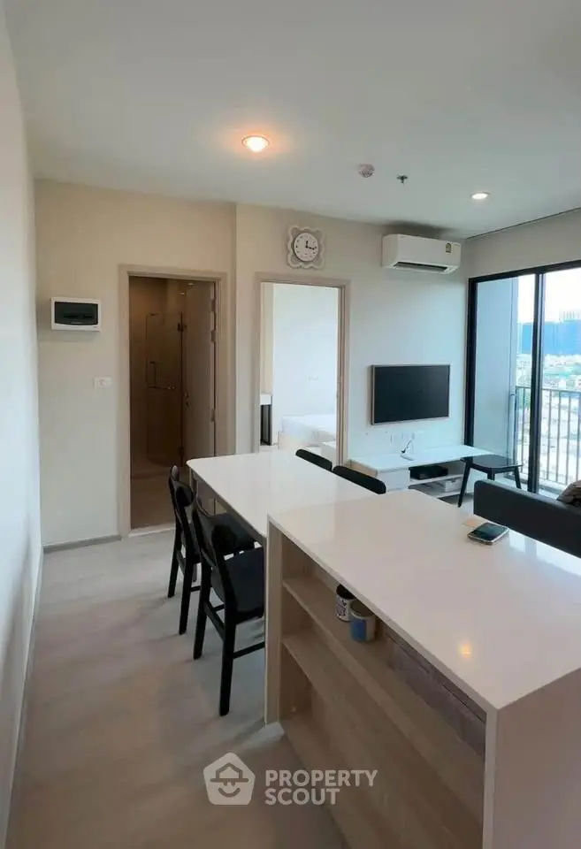 Modern open-plan living room with sleek kitchen island and balcony view.