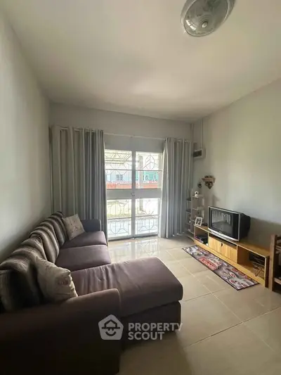 Cozy living room with large sofa and natural light from window, perfect for relaxation.