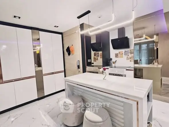 Modern kitchen with sleek white cabinets and marble island, featuring contemporary lighting and stylish decor.