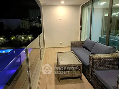 Luxurious balcony with cozy seating overlooking a serene pool, perfect for relaxation and entertaining.