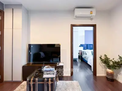 Modern living room with sleek TV setup and view into cozy bedroom