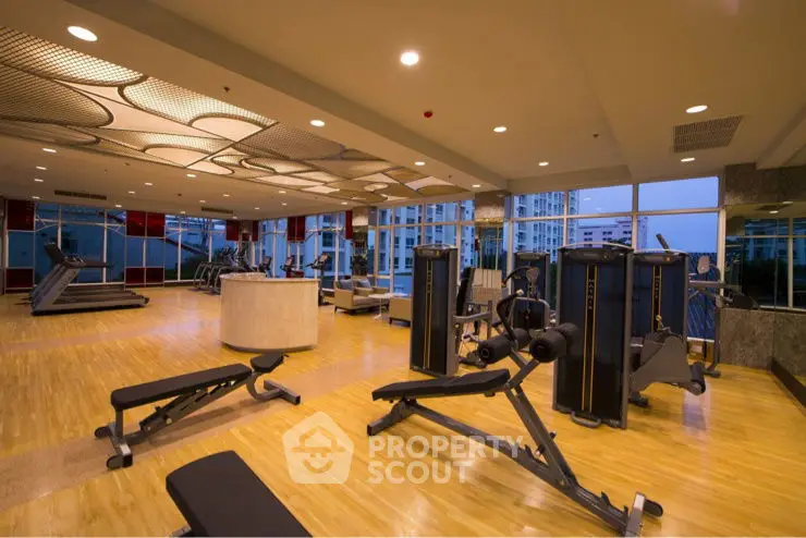 Spacious modern gym with state-of-the-art equipment and city view, perfect for fitness enthusiasts.