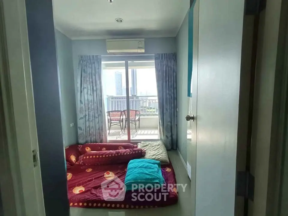 Cozy bedroom with balcony and city view, featuring air conditioning and vibrant bedding.