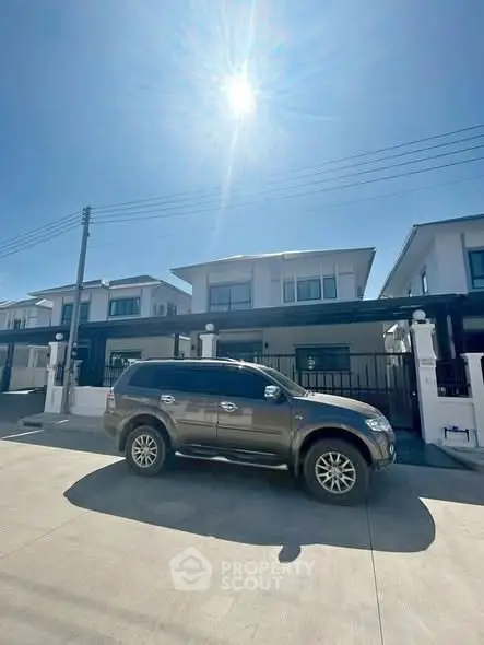 Modern residential building with driveway and parked SUV under clear blue sky.