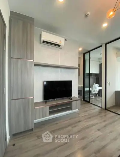 Modern living room with sleek TV setup and air conditioning in stylish apartment.