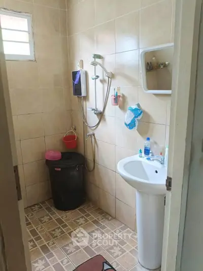 Cozy bathroom with tiled walls, shower, and pedestal sink in a compact layout.