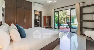 Luxurious bedroom with pool view and modern furnishings in a tropical villa.