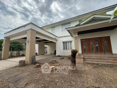 Spacious two-story house with covered parking and wooden entrance, ideal for family living.