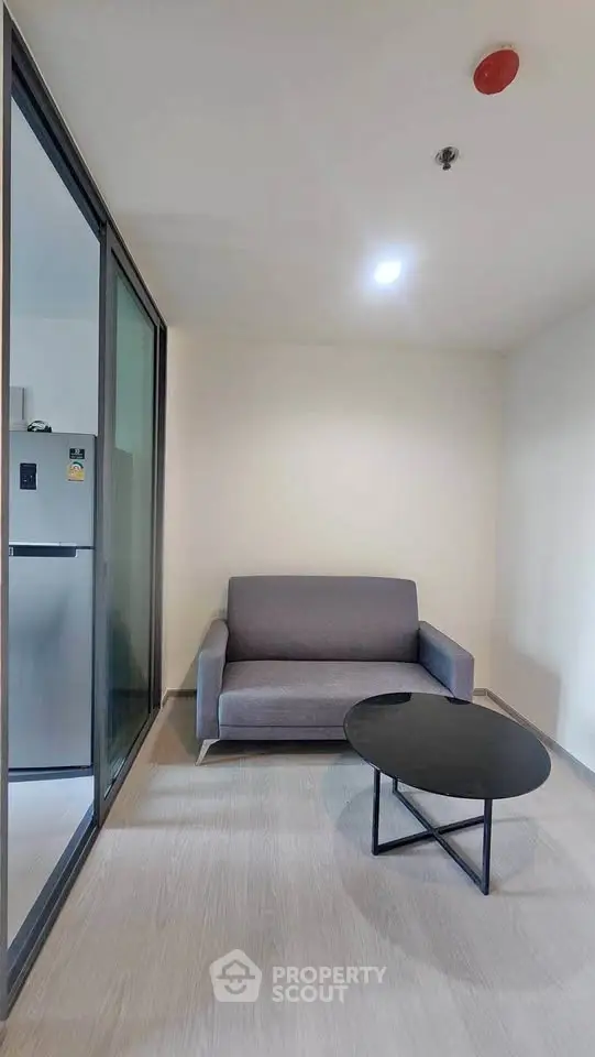 Modern living room with sleek furniture and glass partition in a contemporary apartment.