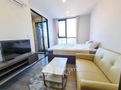 Modern studio apartment with cozy living area and large window view.