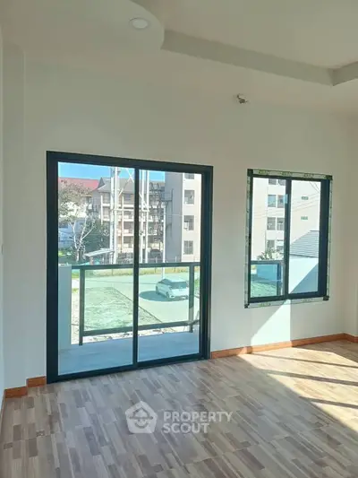 Bright and spacious room with large windows offering a view of the surrounding buildings, perfect for natural light lovers.