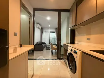 Modern apartment kitchen with open layout and view into cozy living room.