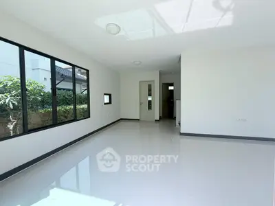 Spacious and bright living room with large windows and glossy tile flooring, perfect for modern living.
