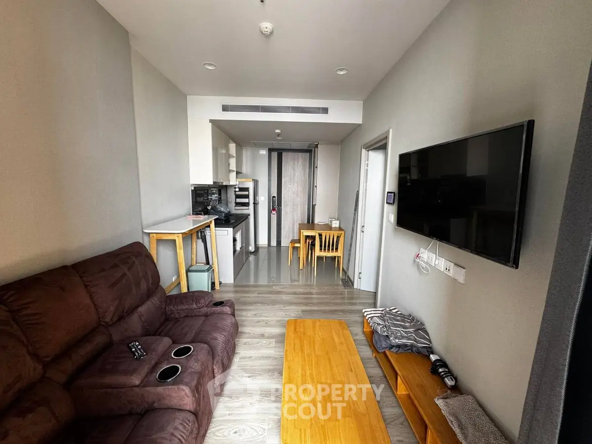 Modern living room with cozy seating and open kitchen layout in a stylish apartment.