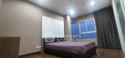 Spacious bedroom with large window and modern decor in high-rise apartment.