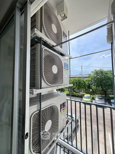 Outdoor view of air conditioning units on a balcony with a scenic background.