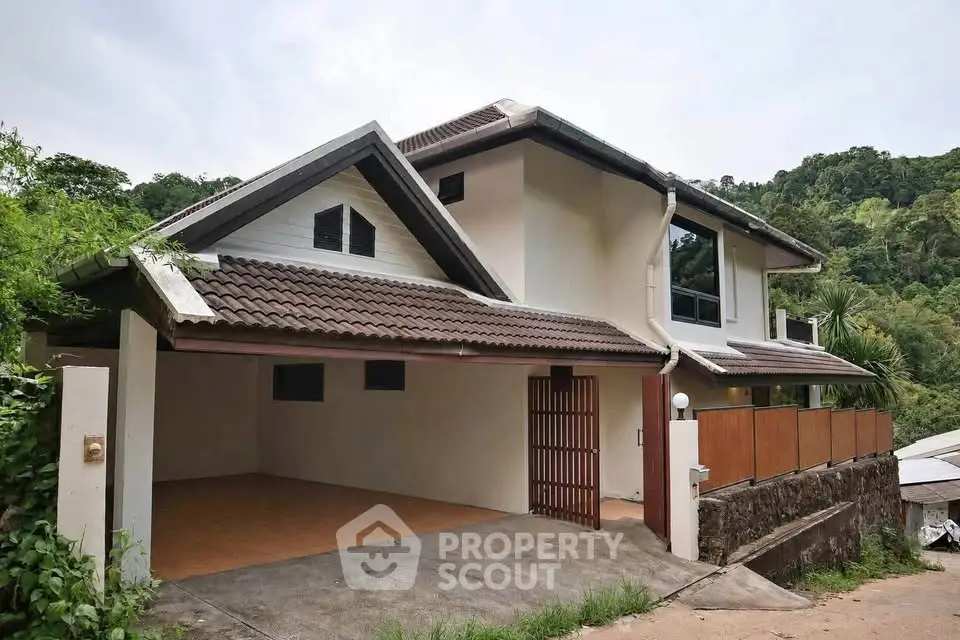 Charming two-story house with sloped roof and spacious garage in lush green setting.
