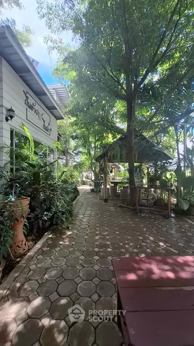 Charming garden pathway with lush greenery and cozy seating area, perfect for relaxation.