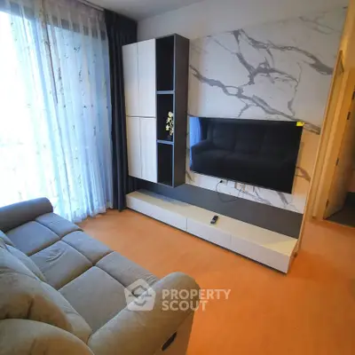 Modern living room with stylish TV setup and cozy sofa, featuring elegant marble accent wall and ample natural light.