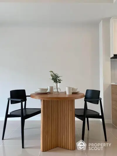 Modern dining area with stylish wooden table and black chairs in minimalist setting.