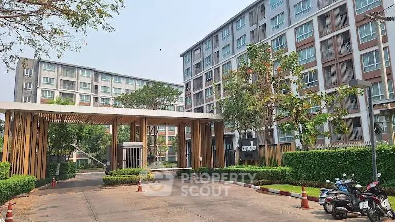 Modern residential building with lush greenery and secure entrance in urban setting.