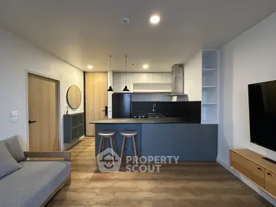 Modern open-layout kitchen with sleek cabinetry and cozy living area, perfect for contemporary living.