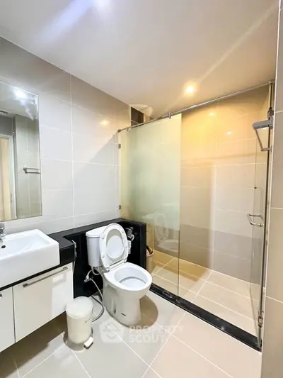 Modern bathroom with glass shower and sleek fixtures in contemporary apartment.