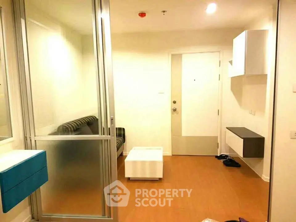 Modern apartment interior with sleek design and cozy living area, featuring a glass partition and stylish furnishings.