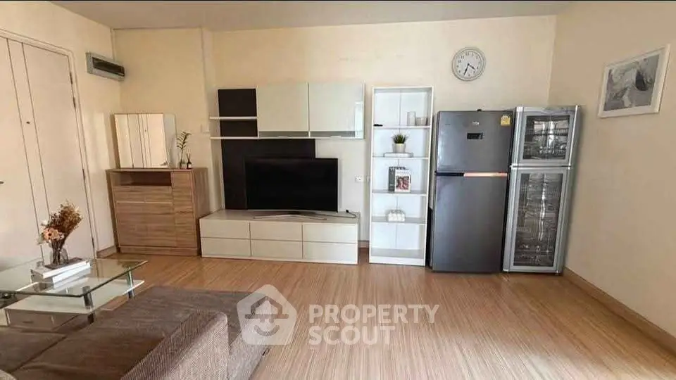 Modern living room with sleek furniture and appliances, featuring a stylish TV unit and refrigerator.