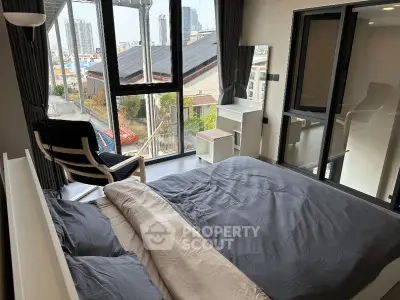 Modern bedroom with large windows and city view, featuring stylish furniture and cozy bedding.