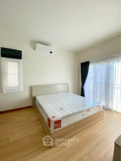 Spacious bedroom with natural light and modern furnishings in a stylish apartment.