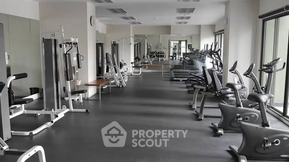 Spacious modern gym with state-of-the-art fitness equipment and large windows for natural light.