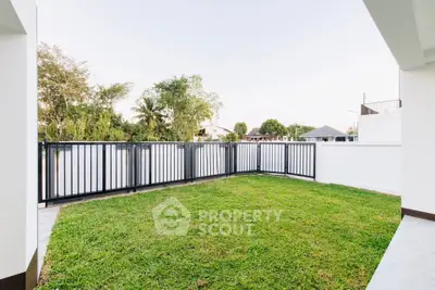 Spacious backyard with lush green lawn and modern fencing in a serene neighborhood.