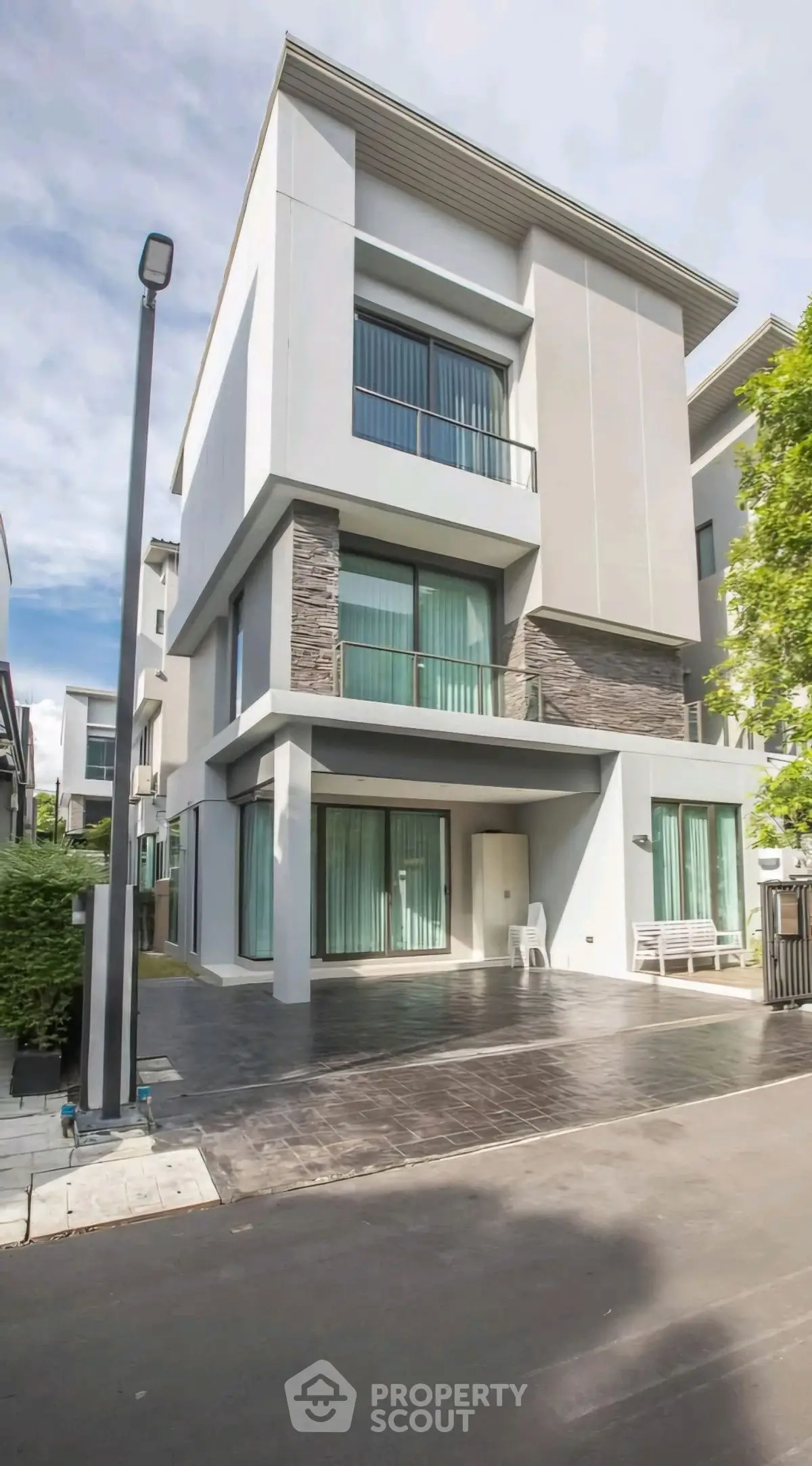 Modern multi-story building with large windows and sleek design in a serene neighborhood.