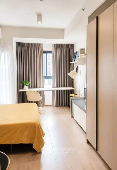 Modern bedroom with study area, large window, and stylish decor in a cozy apartment.