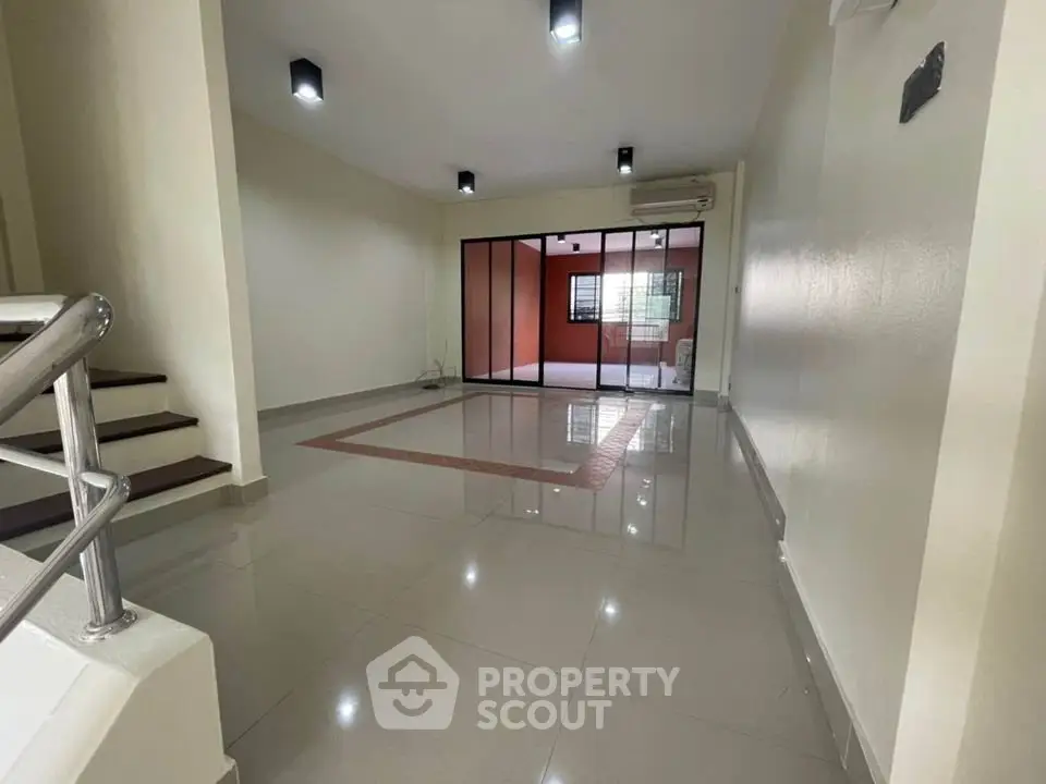 Spacious modern living room with sleek tile flooring and glass partition.