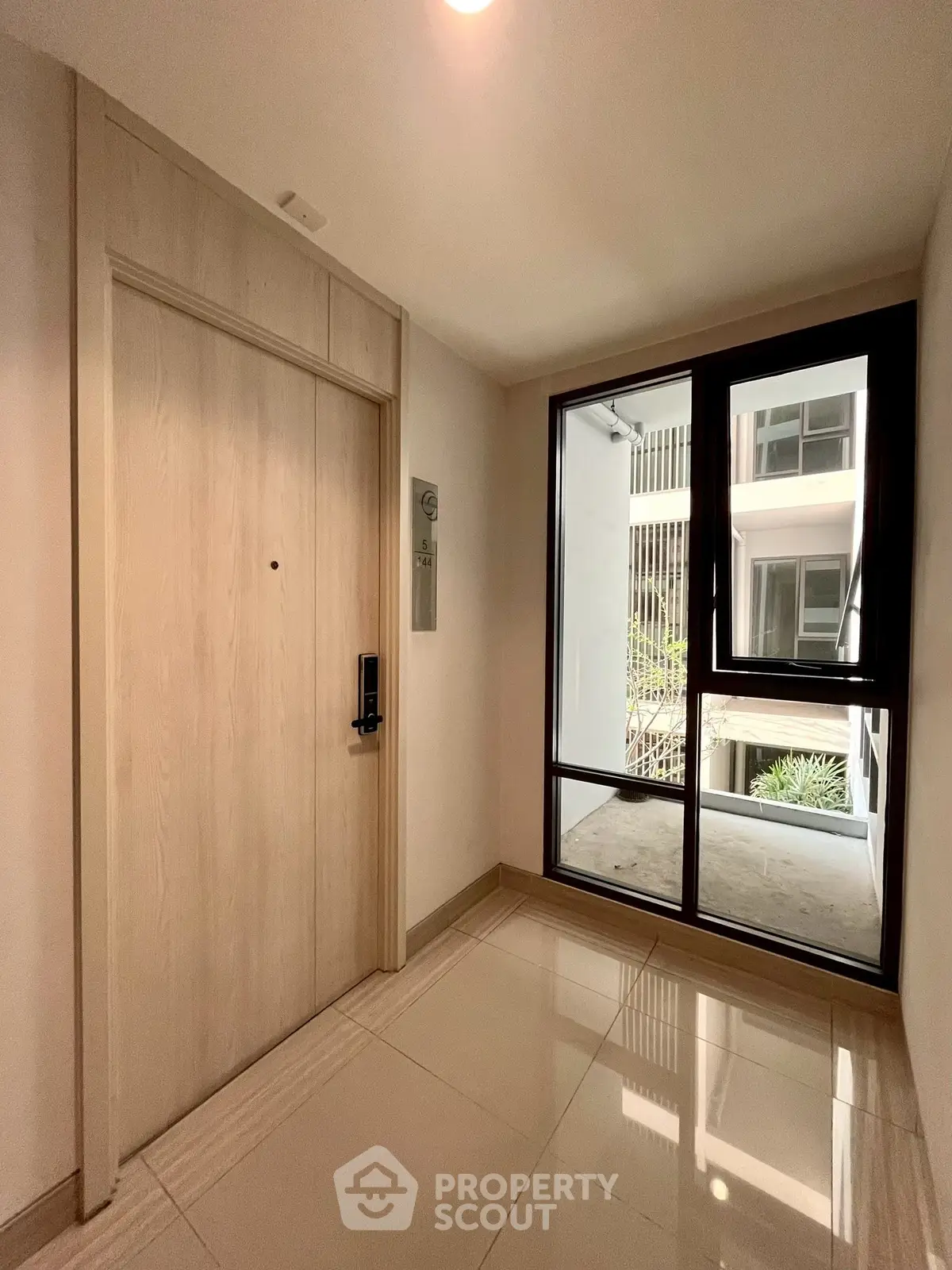 Modern apartment entrance with sleek door and large window offering natural light.