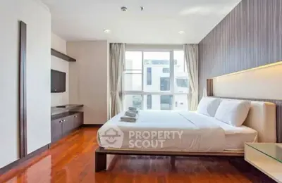 Spacious modern bedroom with large window and elegant wooden flooring