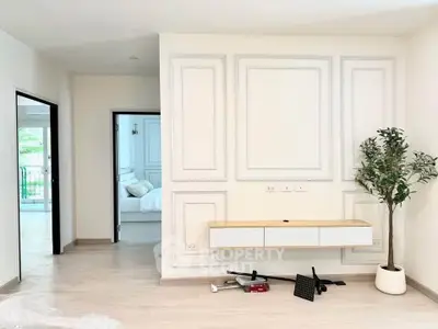 Modern minimalist living room with stylish wall paneling and a glimpse of a cozy bedroom.