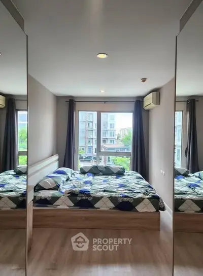 Modern bedroom with large windows and mirrored closet doors, offering a bright and spacious feel.