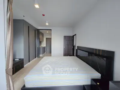 Modern bedroom with sleek design and open kitchen view, perfect for urban living.