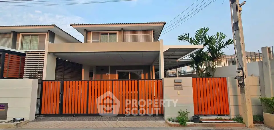 Modern two-story house with orange gate and driveway in a suburban neighborhood.