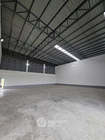 Spacious industrial warehouse with high ceilings and ample natural light, perfect for storage or manufacturing.